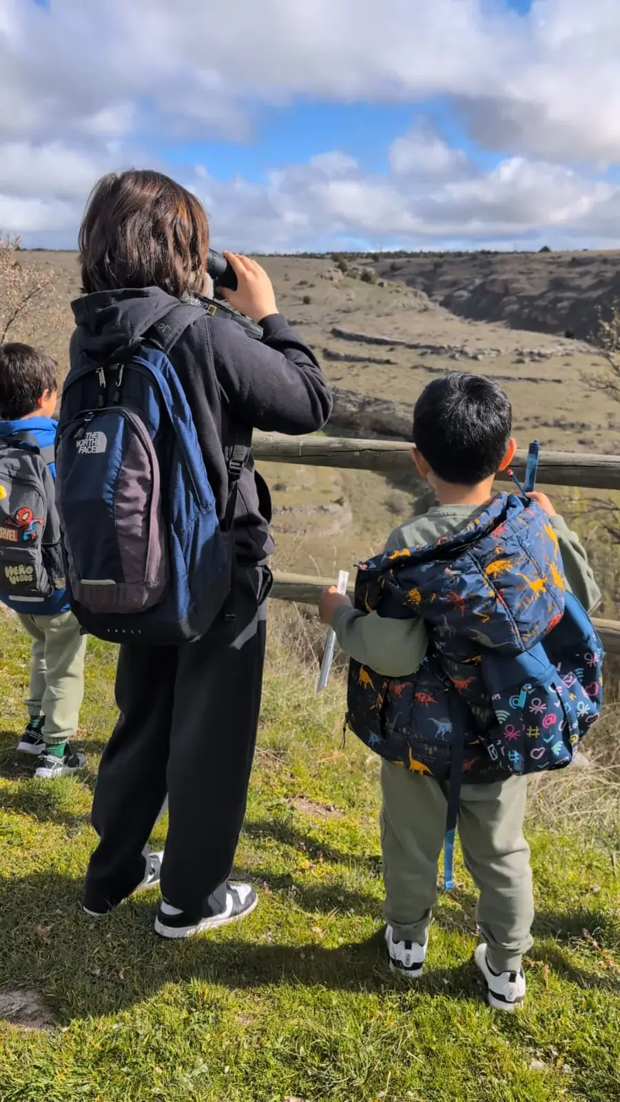 Niños con prismáticos y mochilas explorando el mirador de las hoces